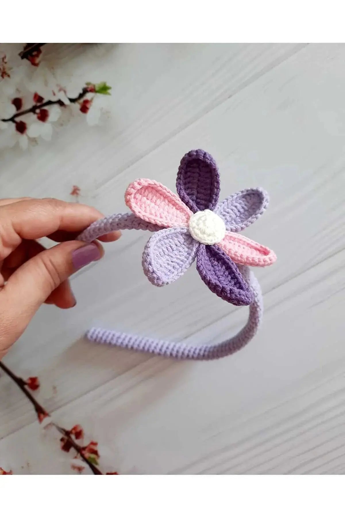 a hand holding a crocheted flower headband