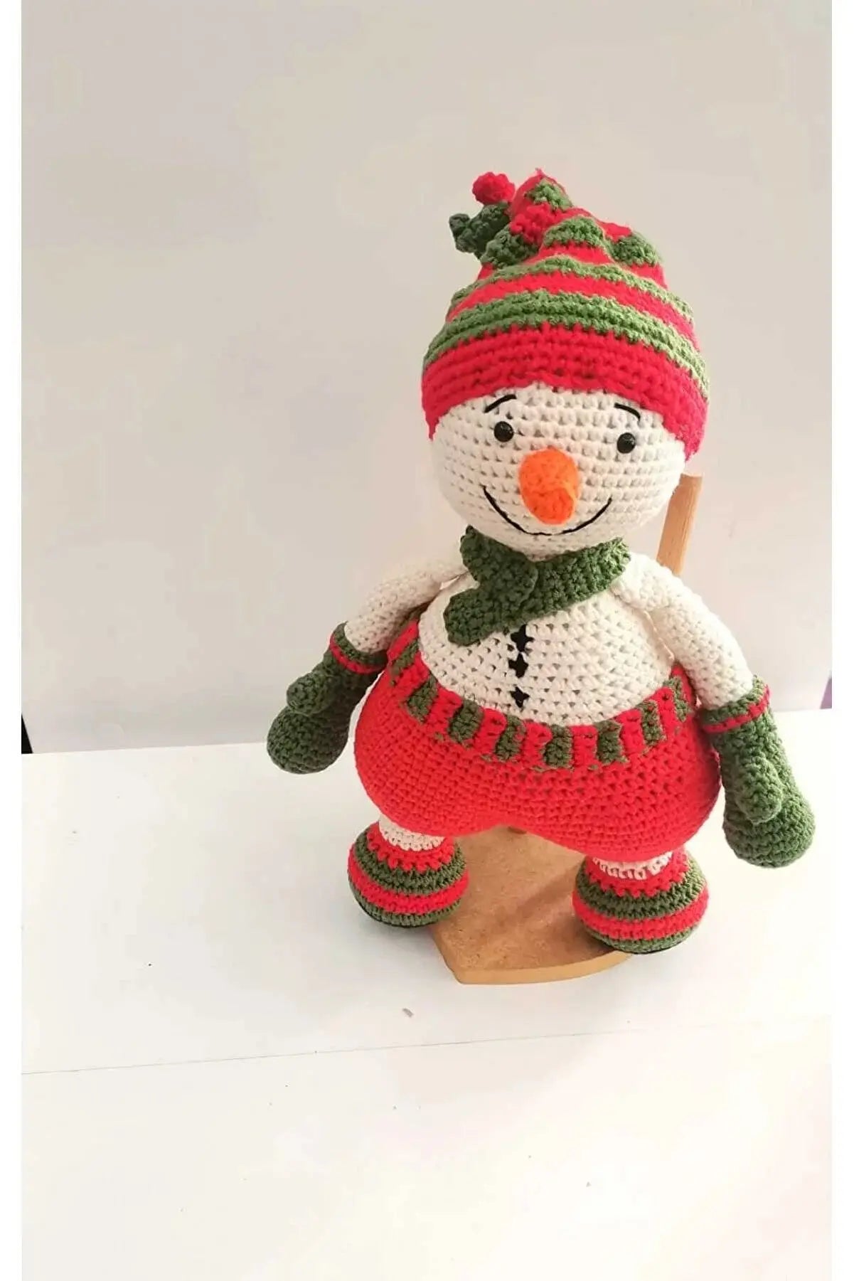 a crocheted snowman sitting on top of a wooden sled