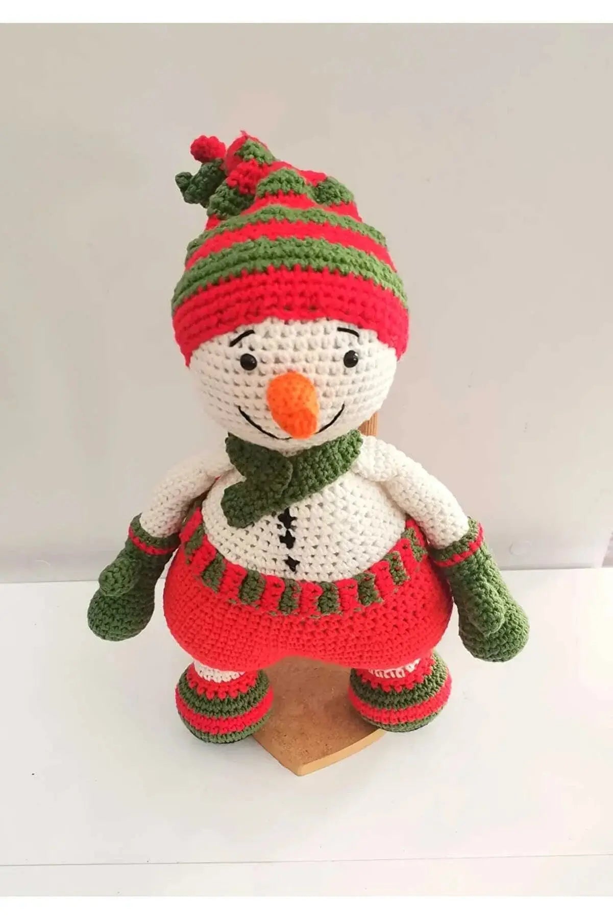 a crocheted snowman sitting on top of a wooden block