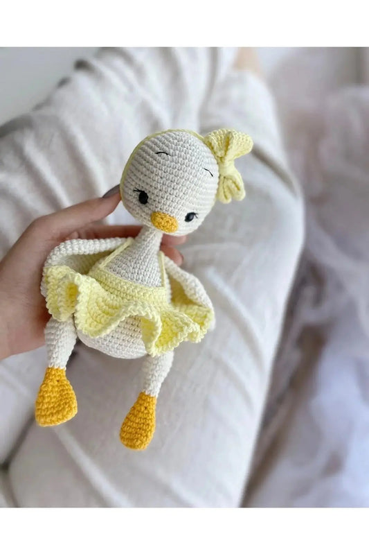 a hand holding a small crocheted stuffed duck