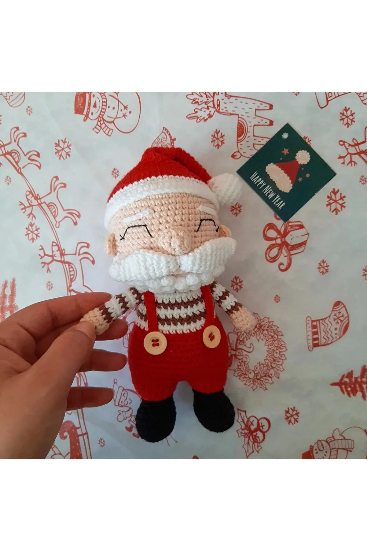 a hand holding a small crocheted santa clause doll