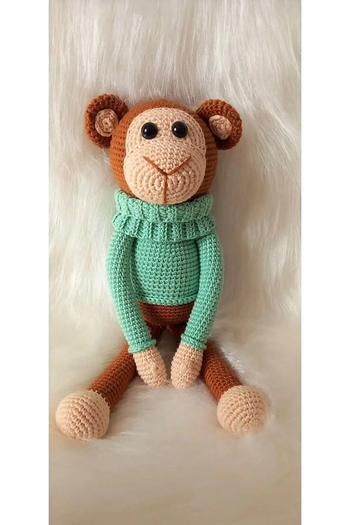 a crocheted monkey wearing a green sweater