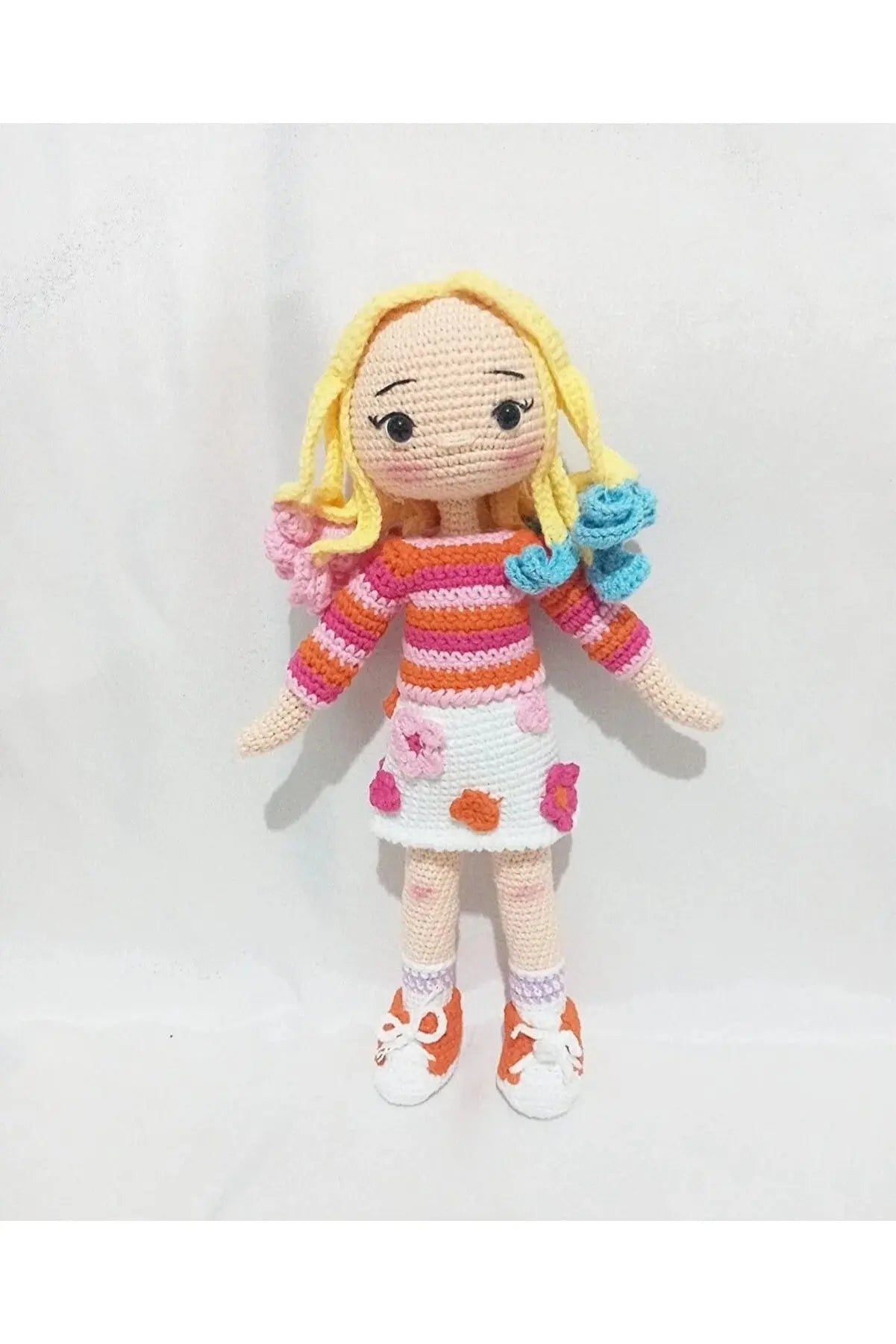 a crocheted doll with yellow hair and orange shoes