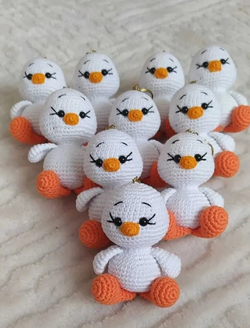 a group of small white crocheted birds sitting on a bed