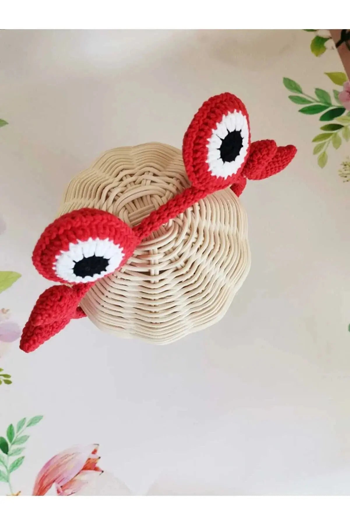 a crocheted red crab with a black eye on it's head