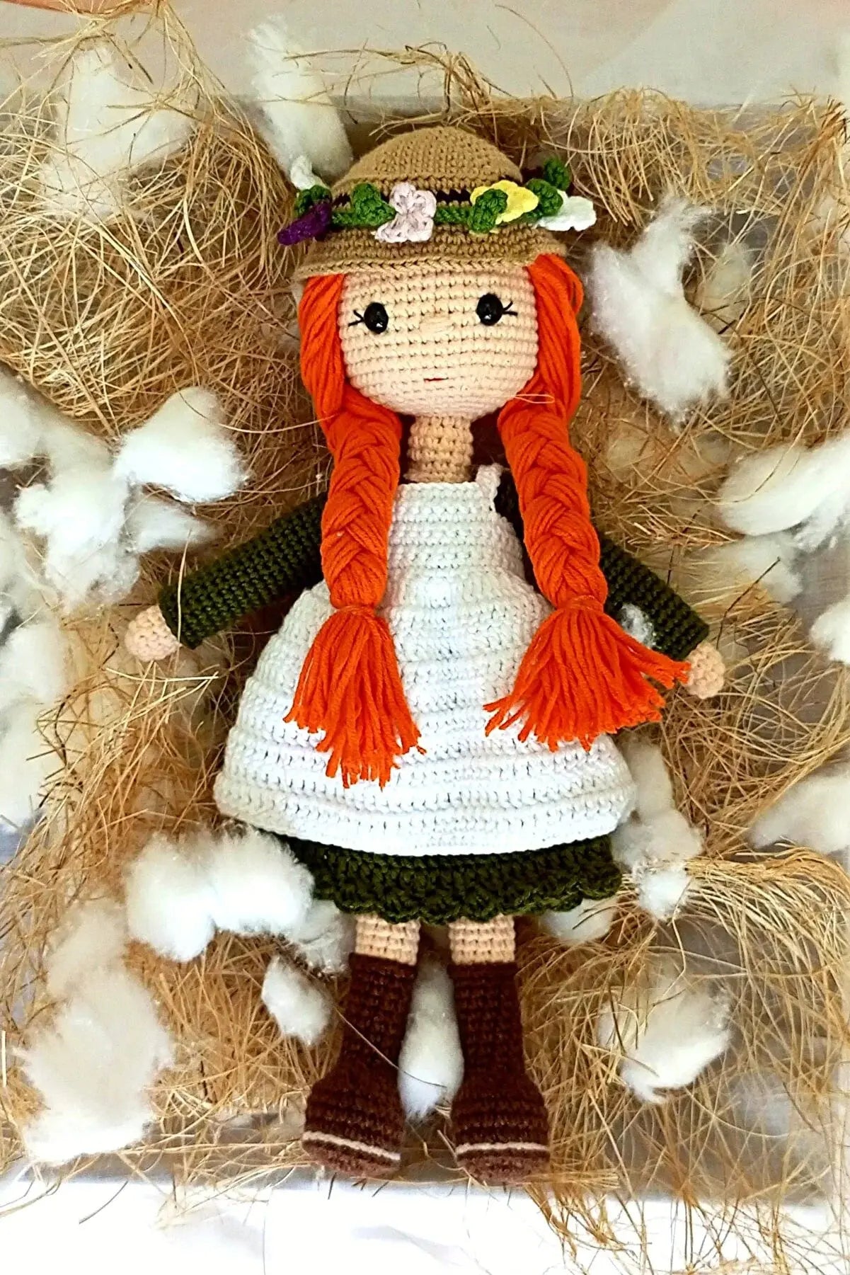 a crocheted doll in a box of hay