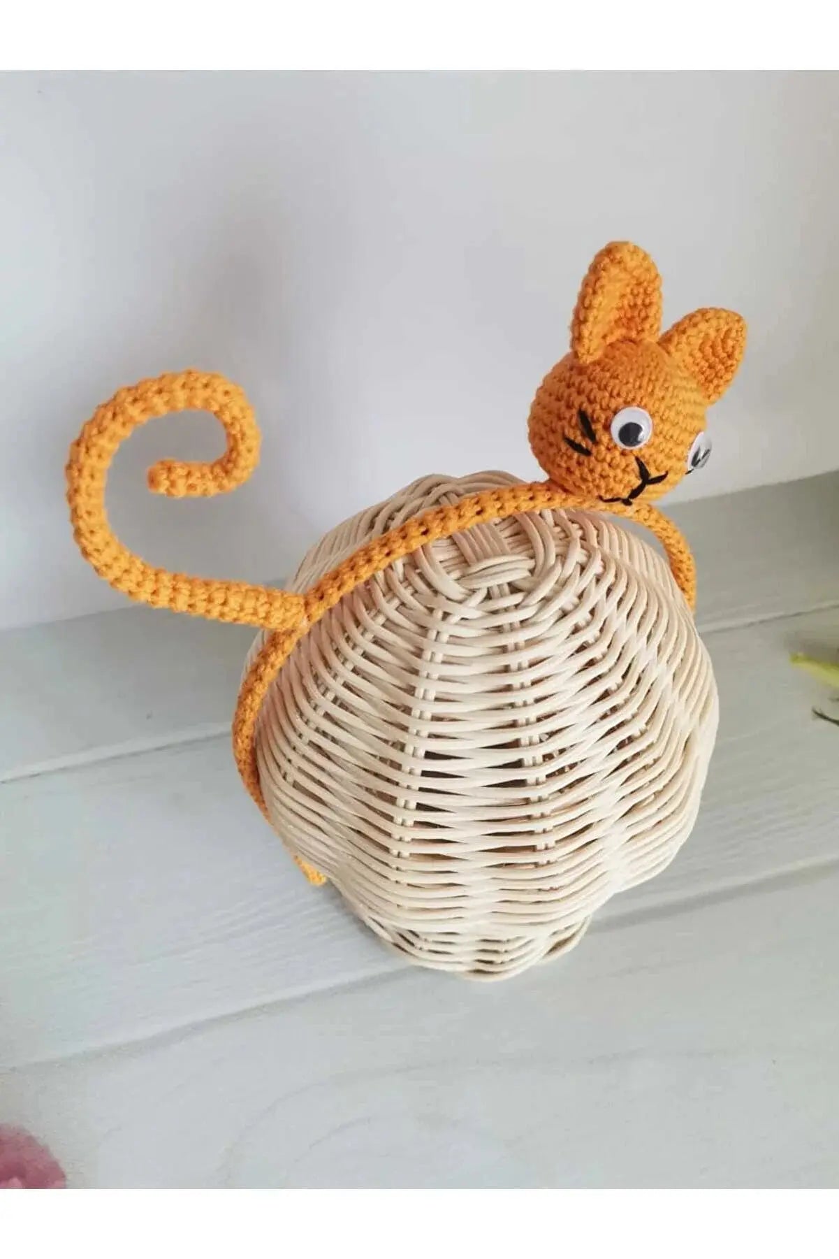 a crocheted cat sitting on top of a basket