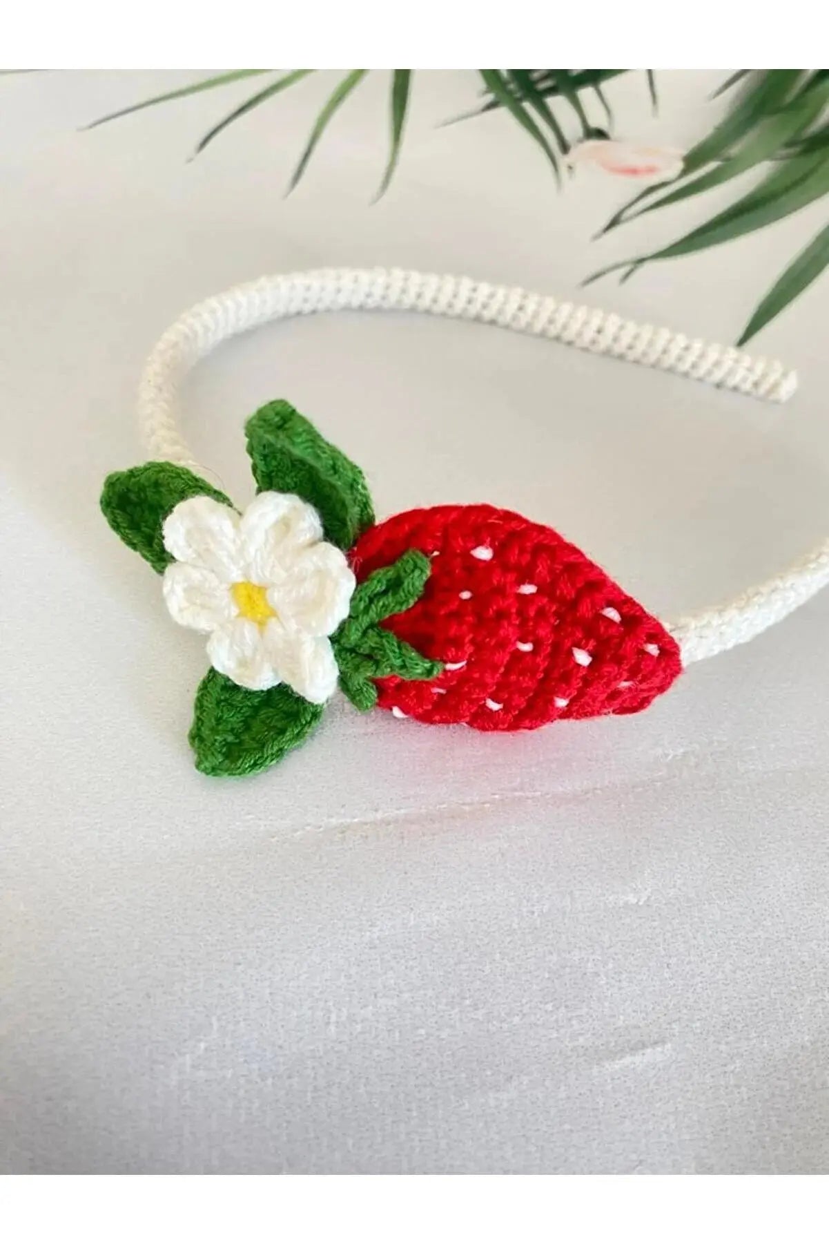 a crocheted strawberry headband with a flower on it