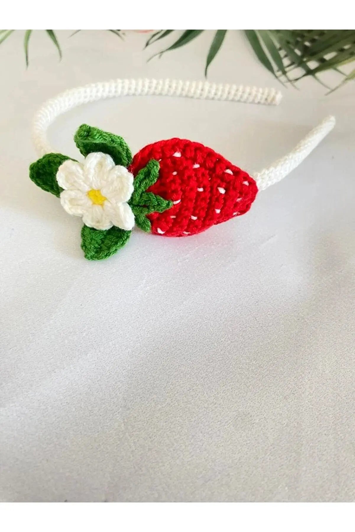 a crocheted strawberry headband with a flower on it