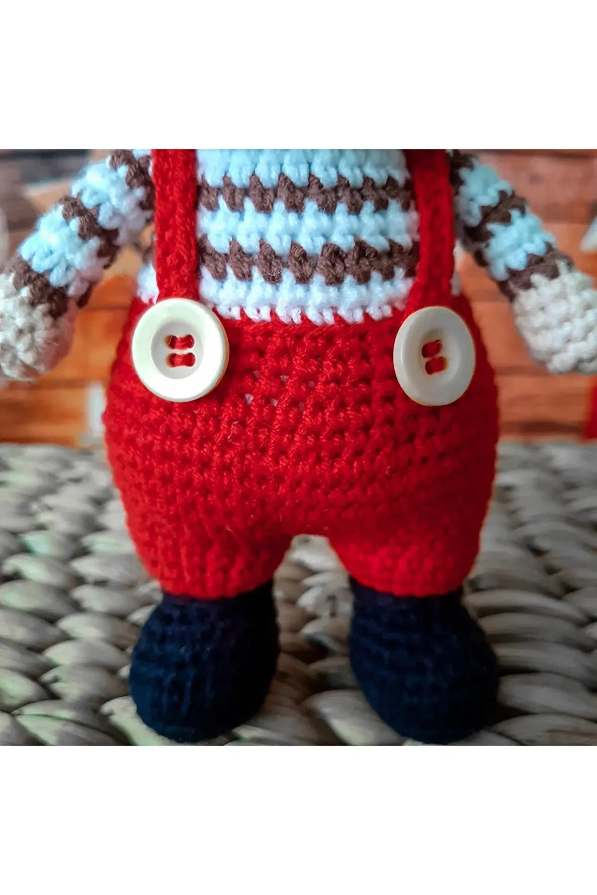 a crocheted stuffed animal wearing a red overall