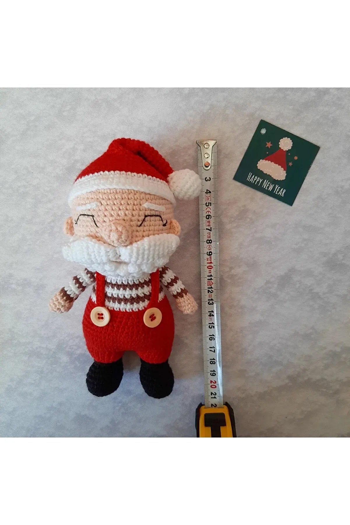 a knitted santa claus doll next to a ruler