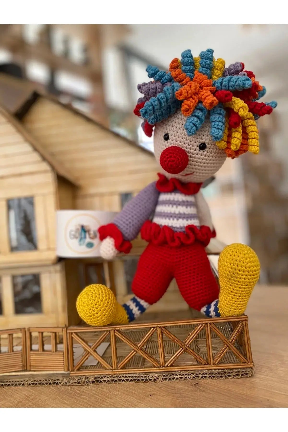 a crocheted clown doll on a wooden table