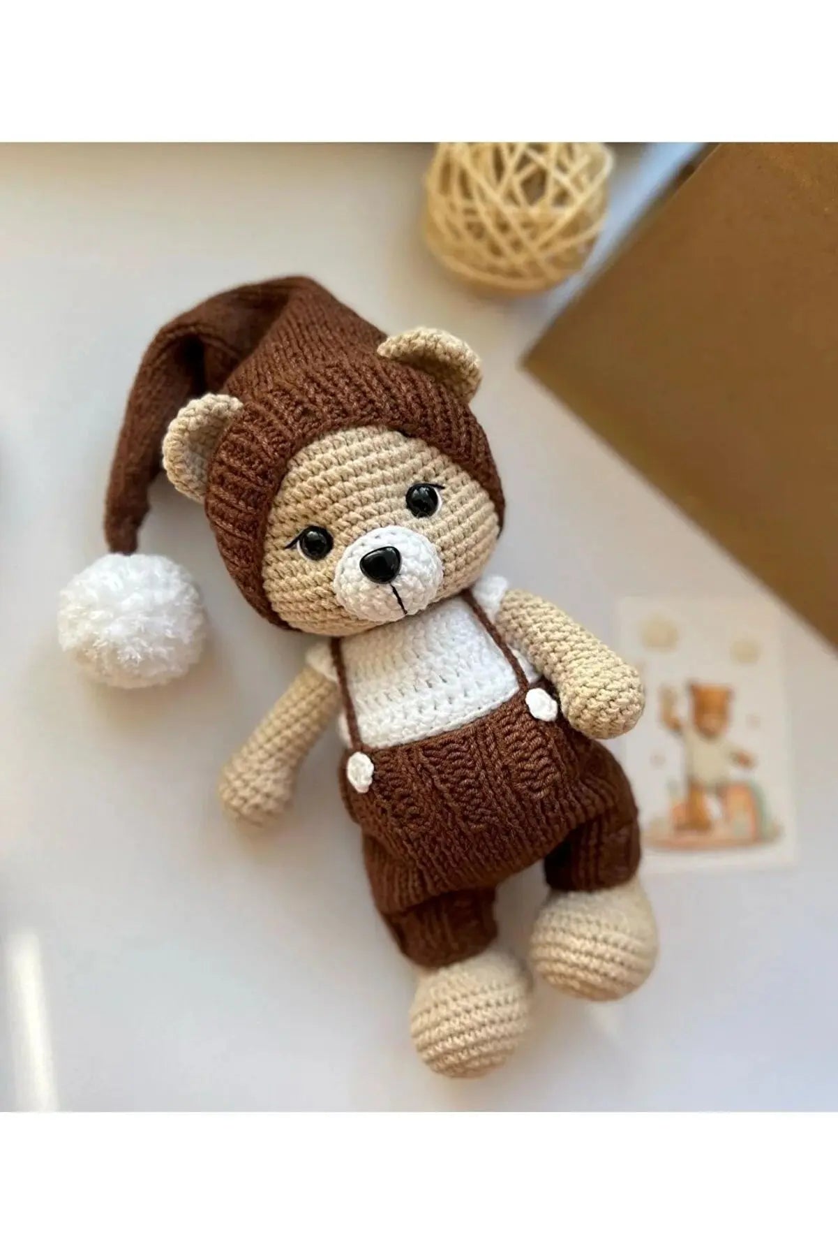 a crocheted teddy bear wearing a brown hat