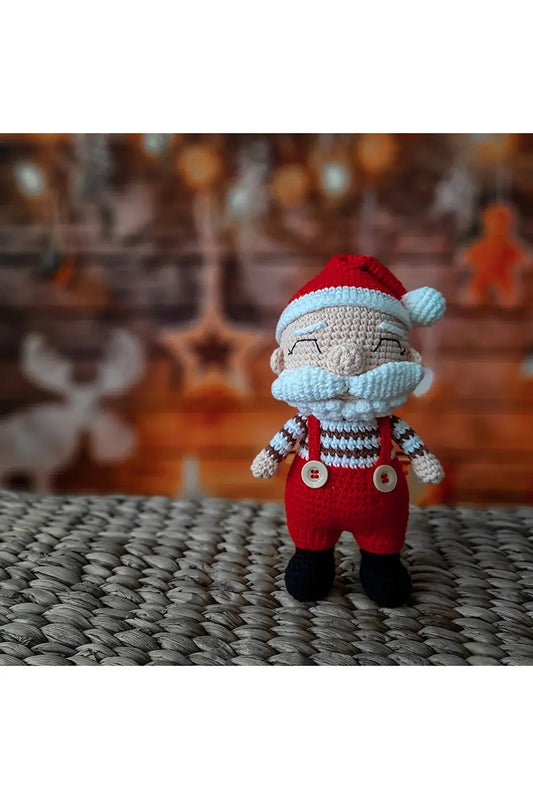 a knitted santa clause doll sitting on a bed