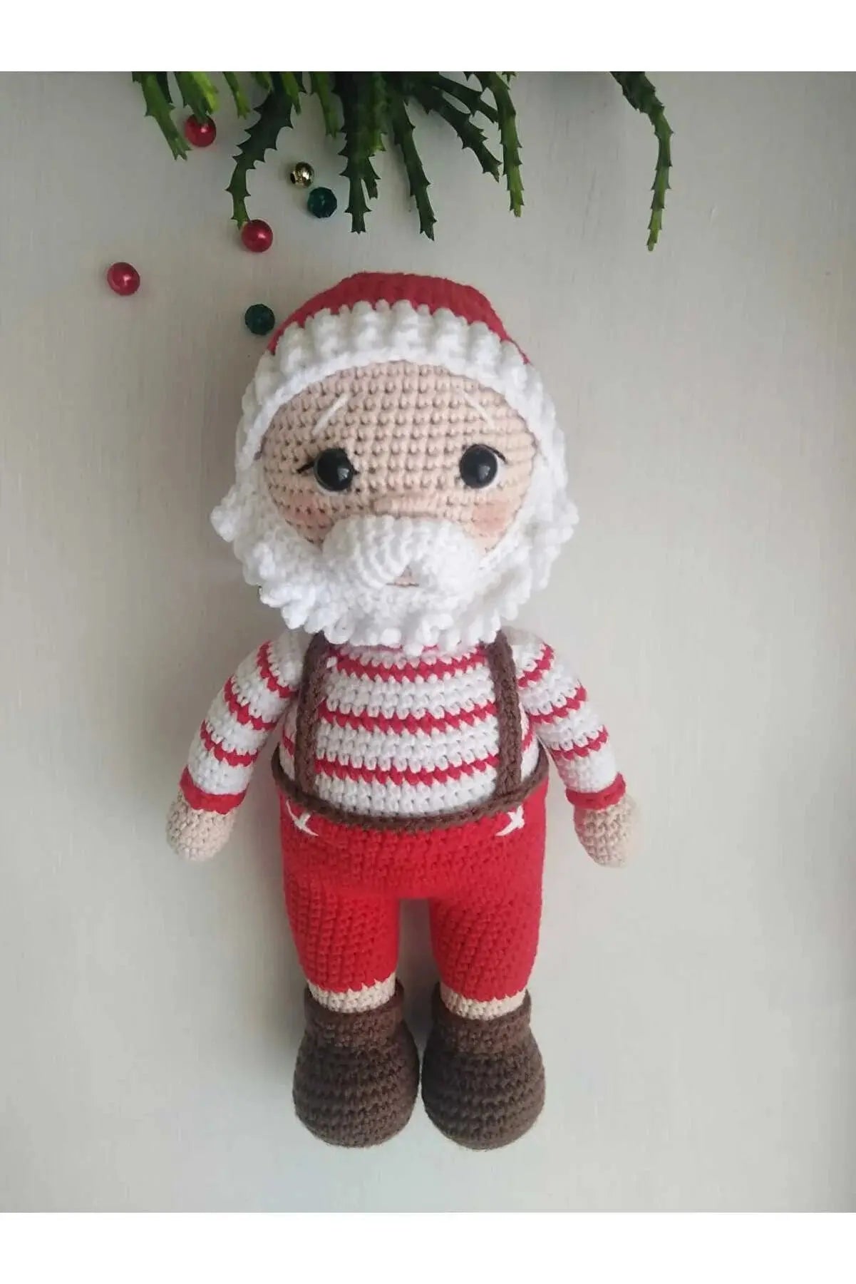 a crocheted santa clause doll hanging on a wall