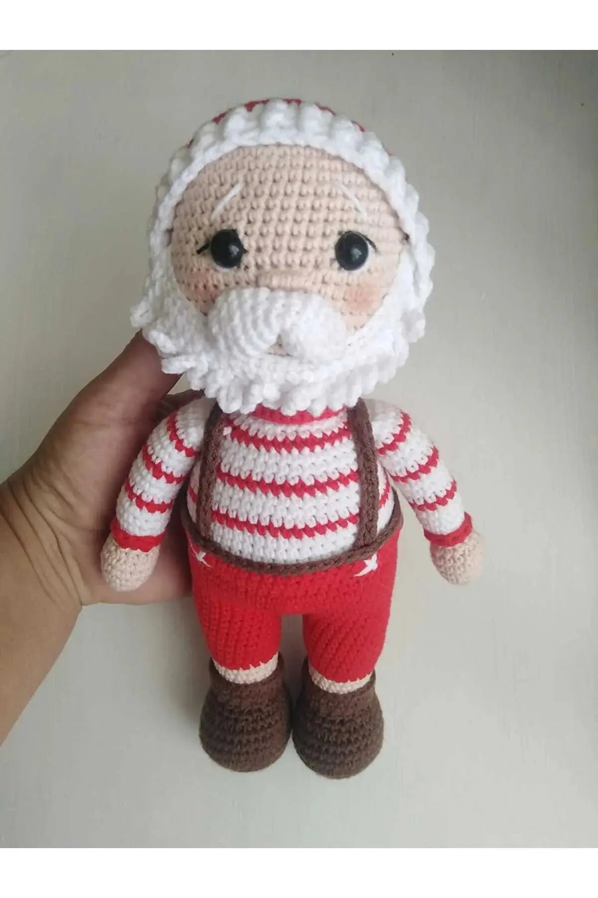 a hand holding a small crocheted santa clause doll