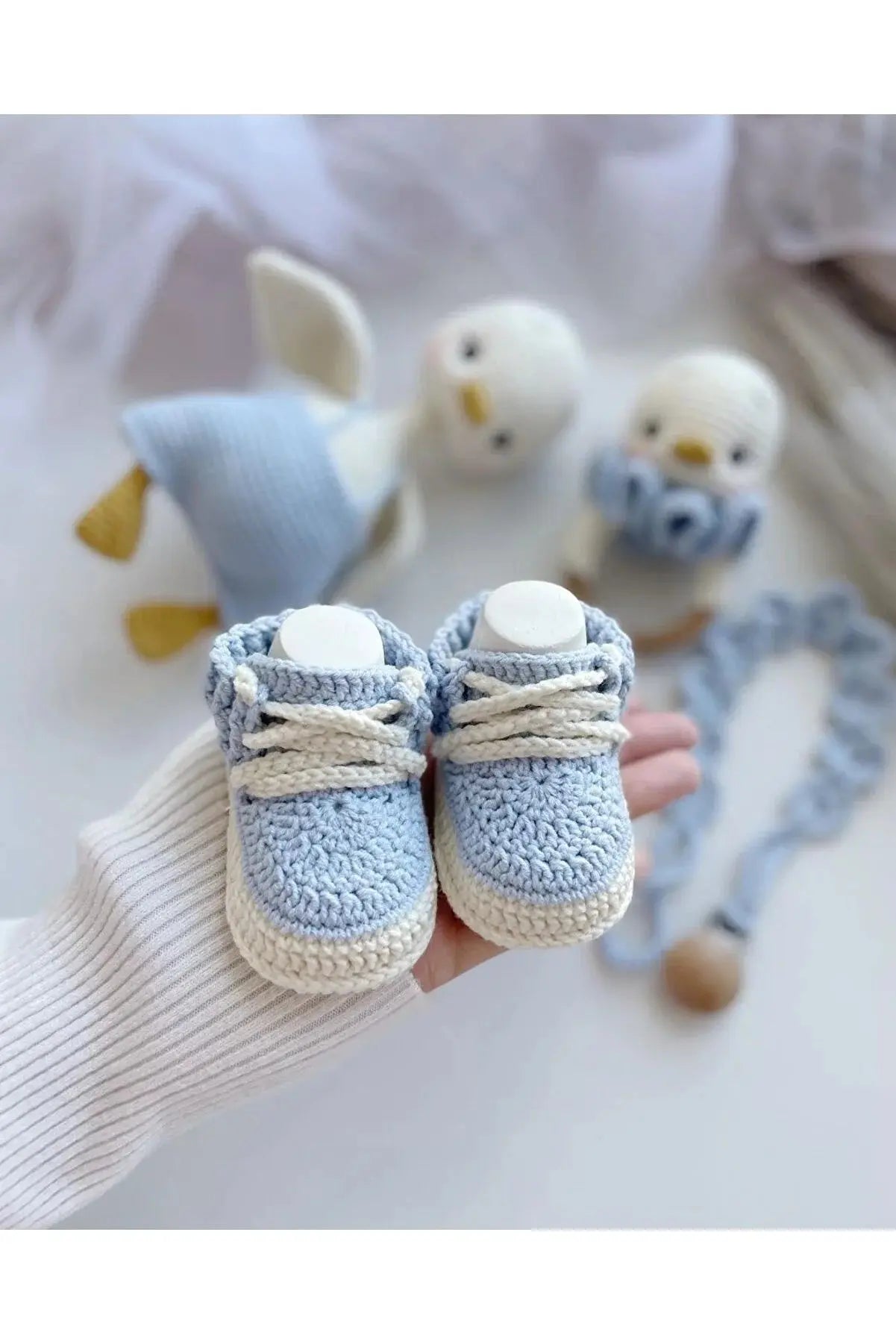 a child's hand holding a pair of baby shoes