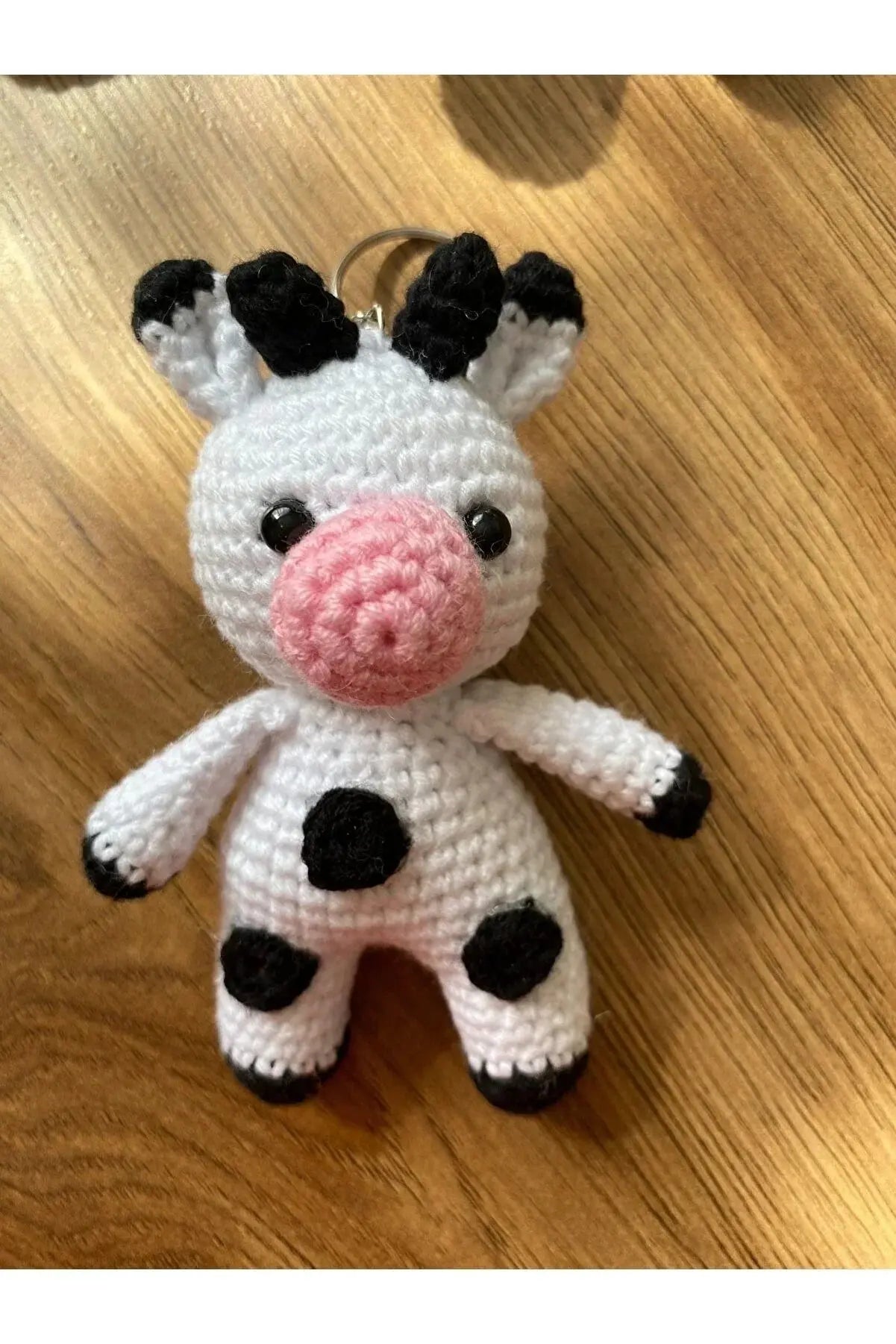 a crocheted cow ornament on a wooden table