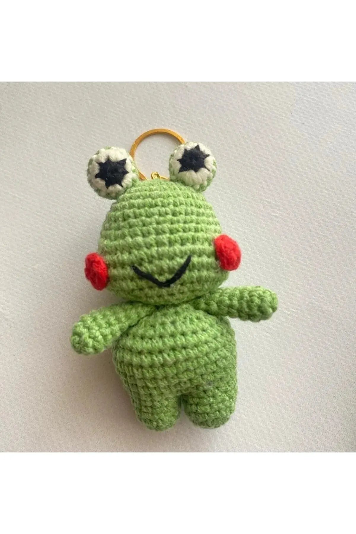 a crocheted frog keychain with a smiley face