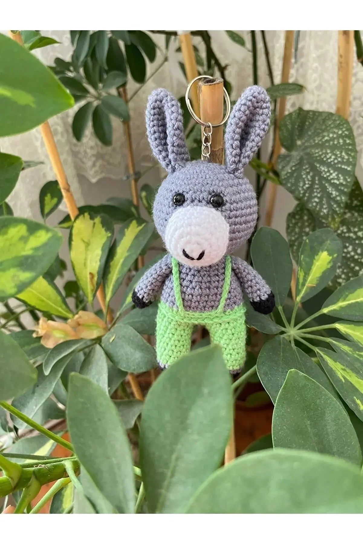 a crocheted donkey keychain hanging from a plant