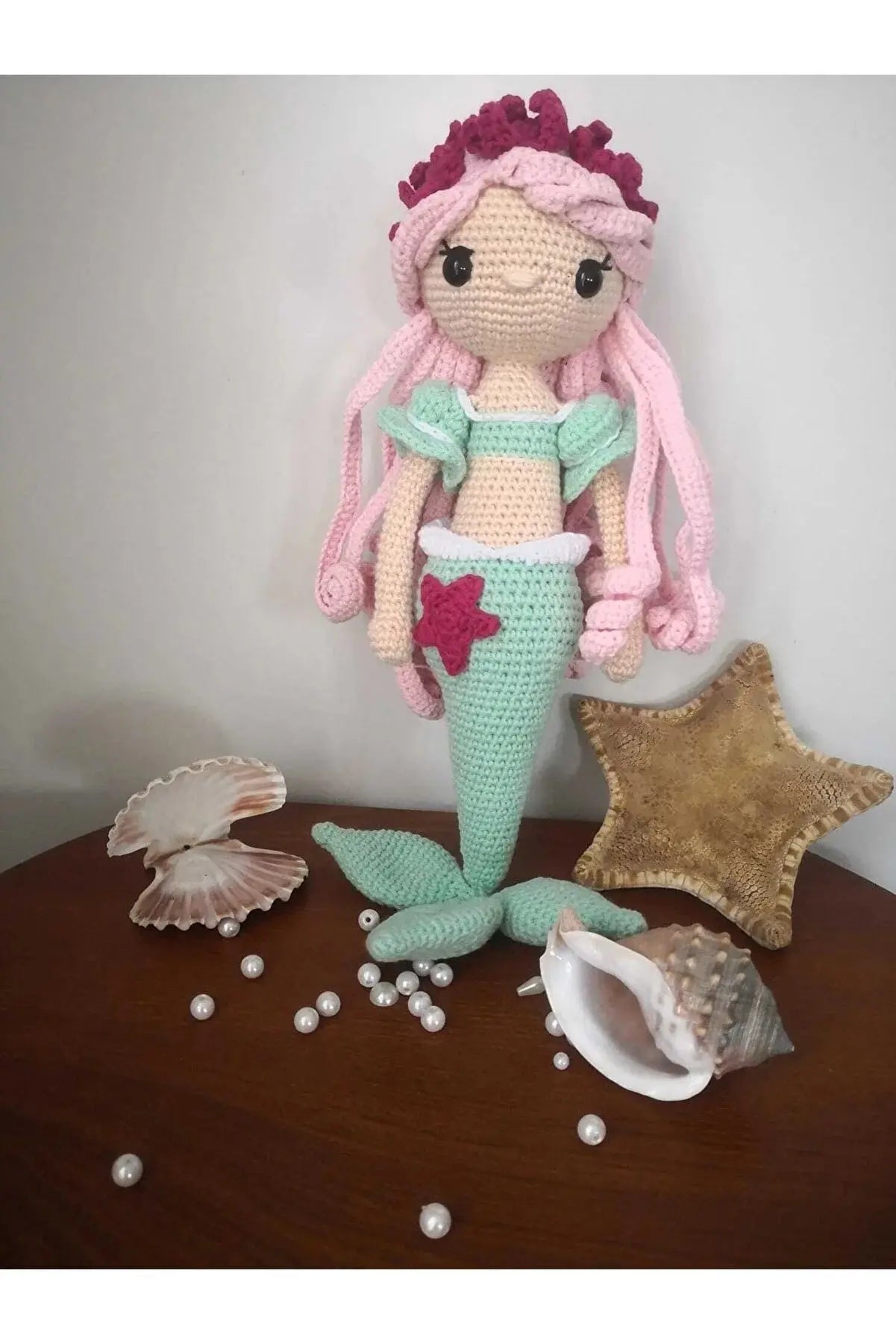 a crocheted mermaid doll sitting on top of a wooden table