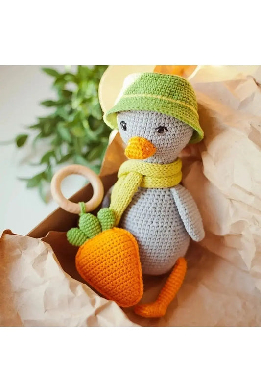 a crocheted stuffed penguin holding a carrot