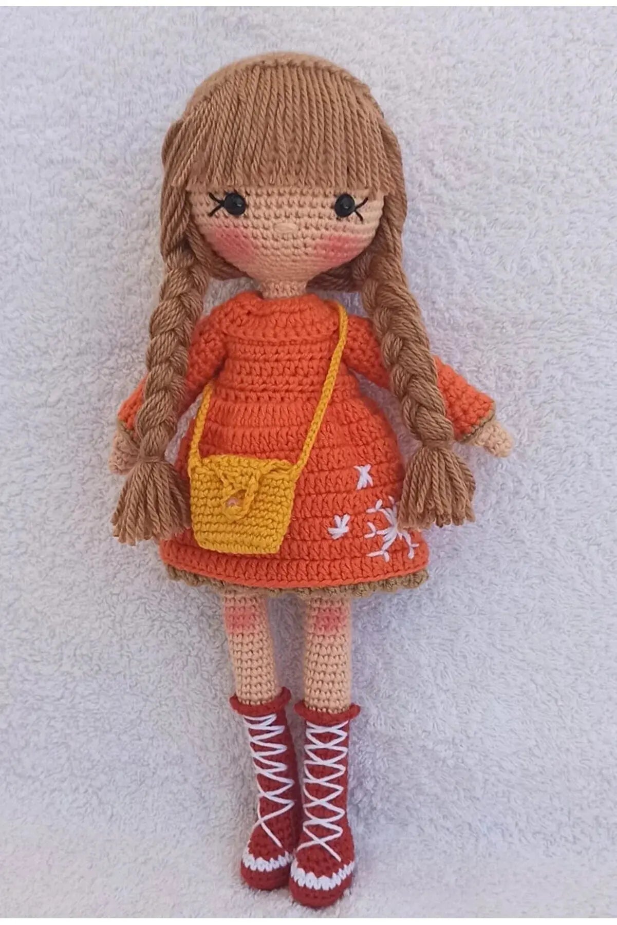 a crocheted doll wearing a red dress and red boots