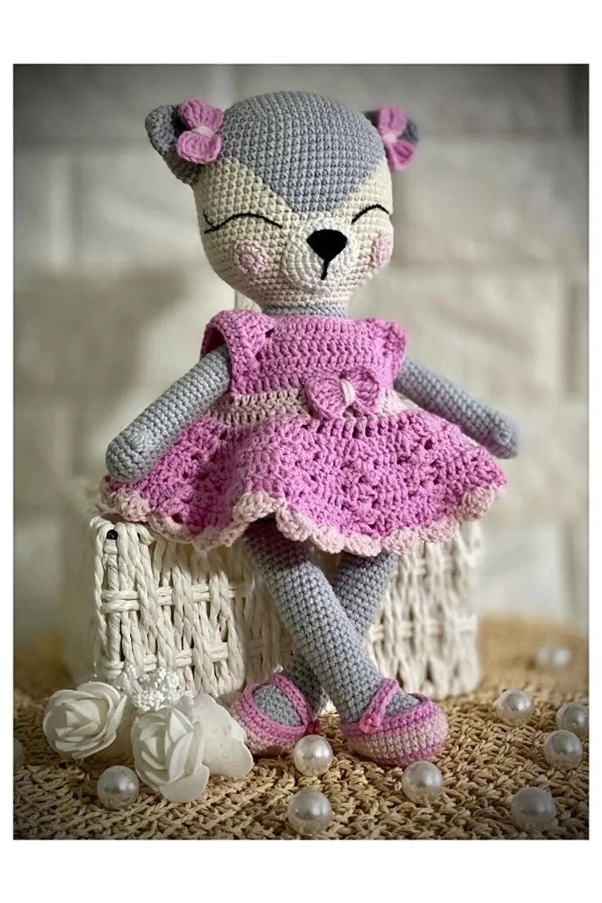 a crocheted teddy bear wearing a pink dress