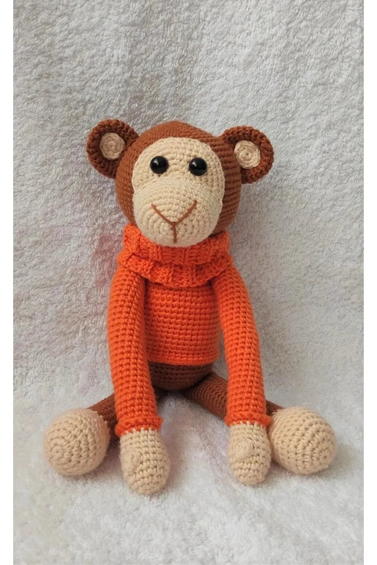 a crocheted monkey sitting on top of a white blanket