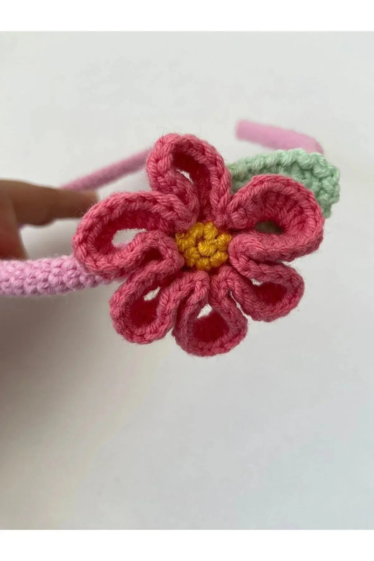 a crocheted flower is being held by a person