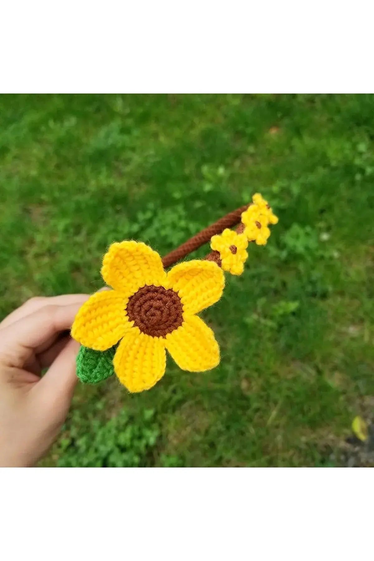 a hand holding a crocheted yellow flower