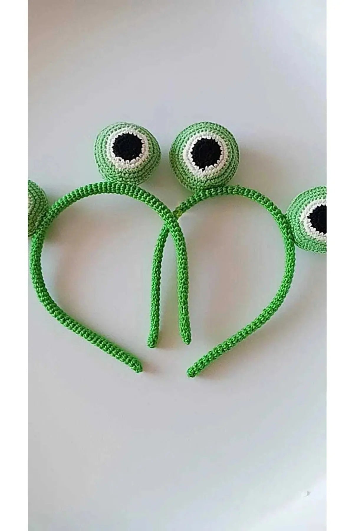 a pair of green eyeball headbands on a white surface