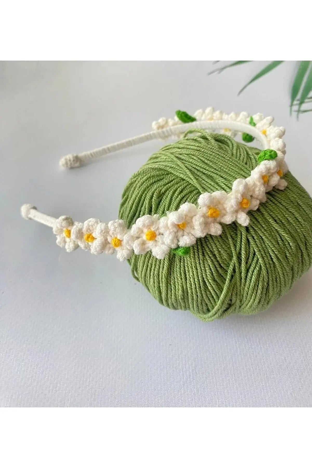 a green ball of yarn with white flowers on it