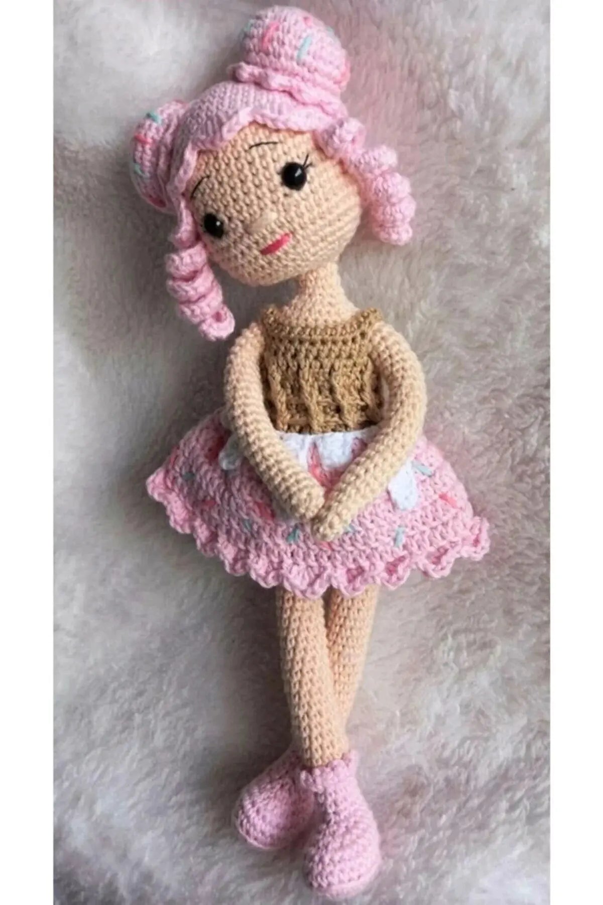 a crocheted doll with pink hair and a pink dress