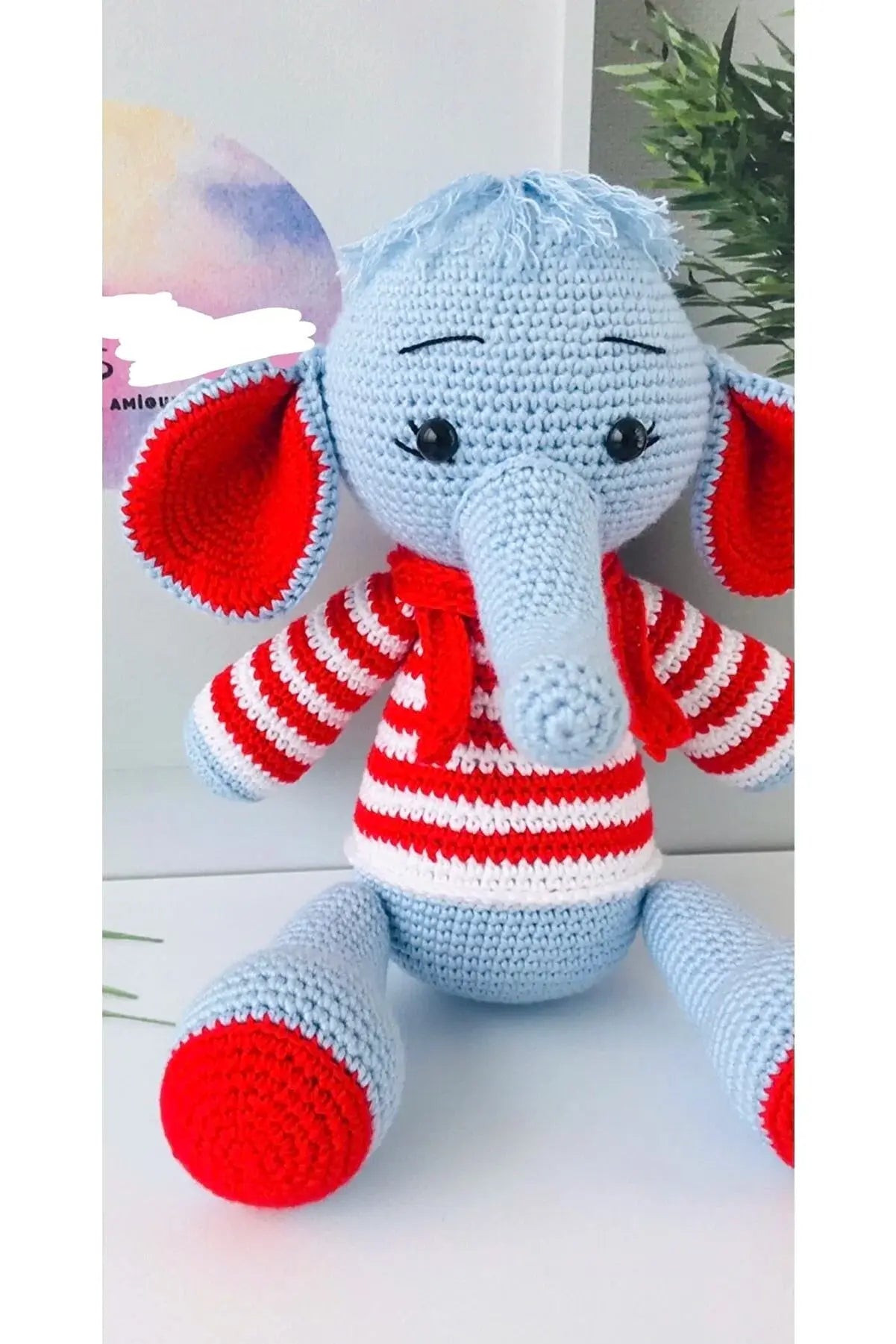 a crocheted stuffed elephant wearing a red and white striped shirt