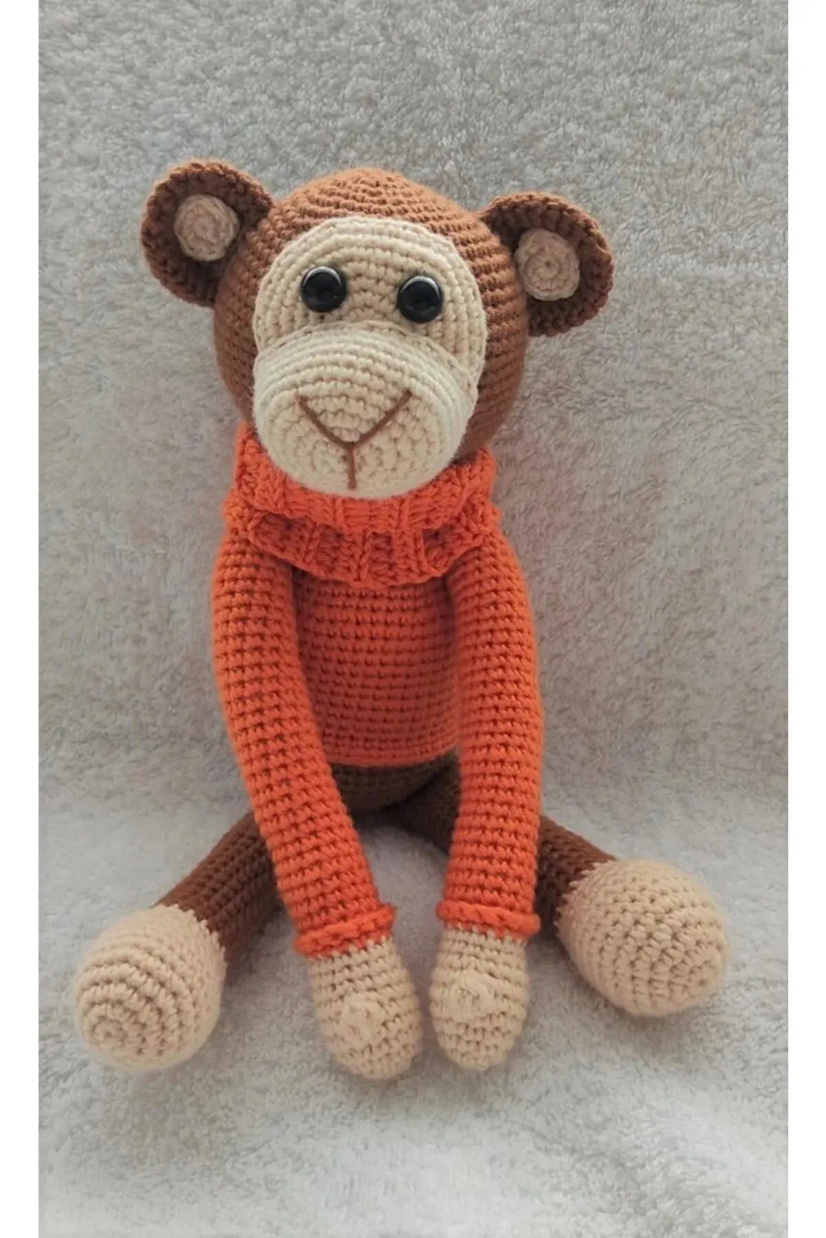 a crocheted monkey sitting on a white surface