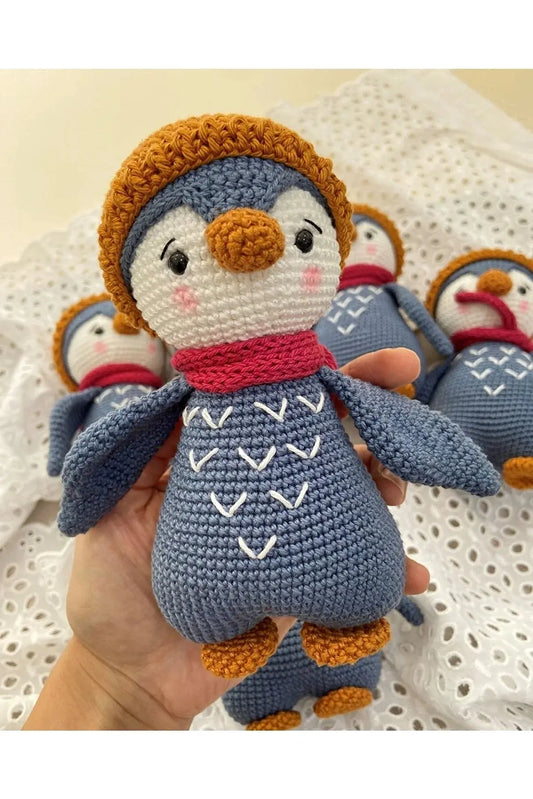 a hand holding a crocheted stuffed penguin