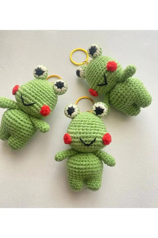 a group of crocheted frog keychains on a table