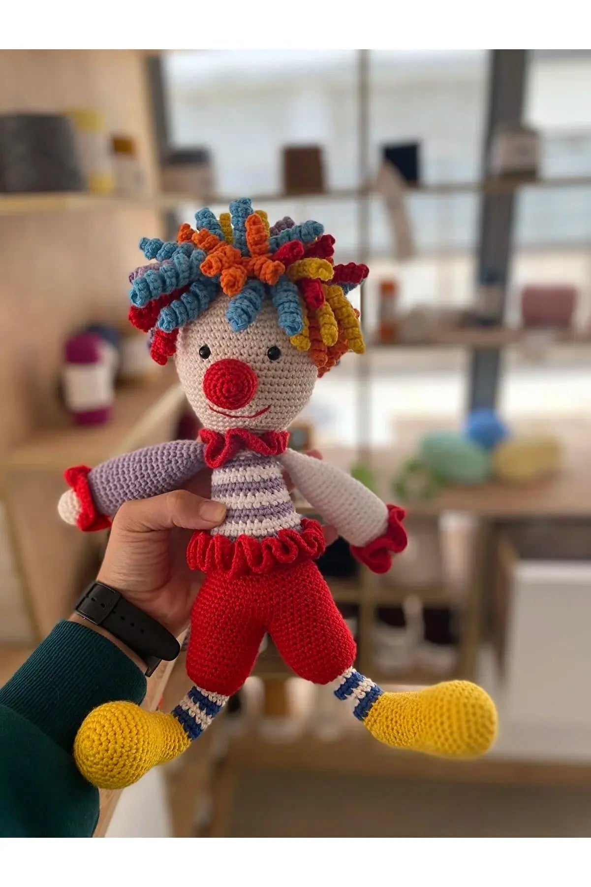 a person holding a knitted clown doll