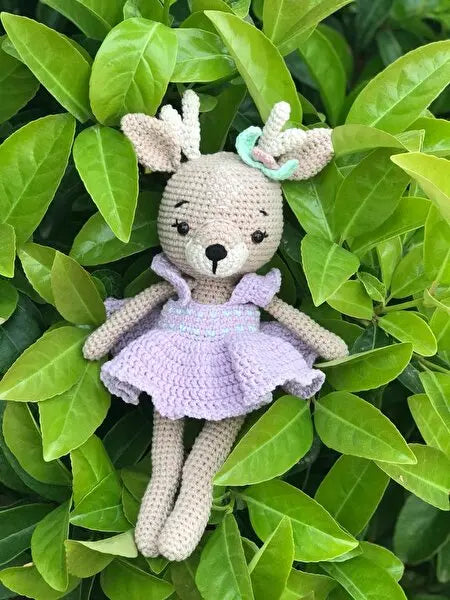 a crocheted stuffed animal wearing a purple dress