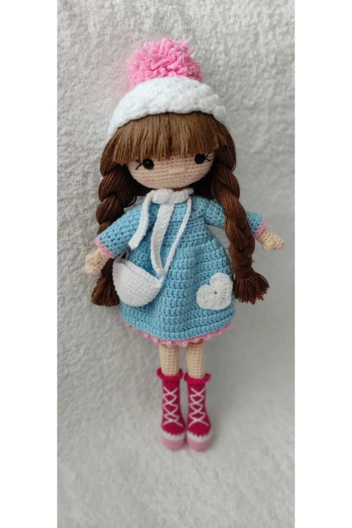 a crocheted doll with a pink hat and blue dress