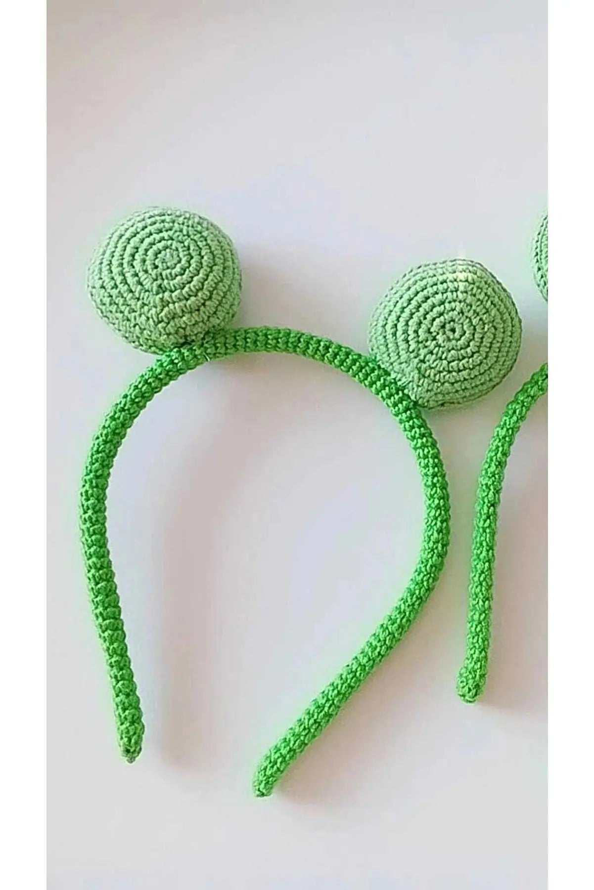 a crocheted green headband with two balls on it