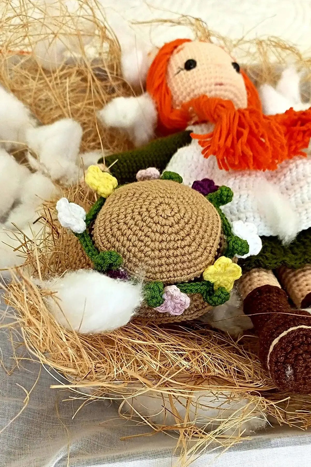 a crocheted doll laying on top of a pile of hay