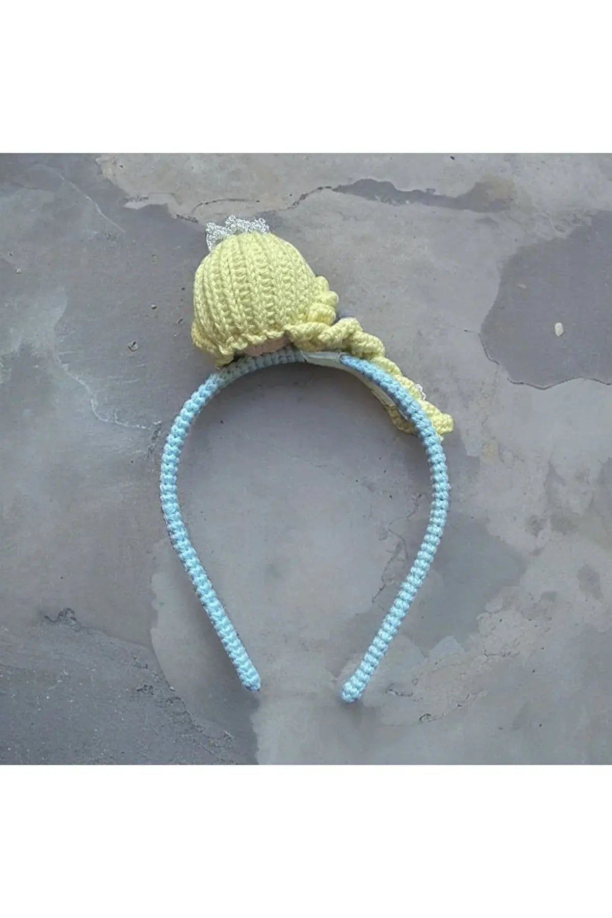 a yellow and blue knitted hat laying on top of a rock