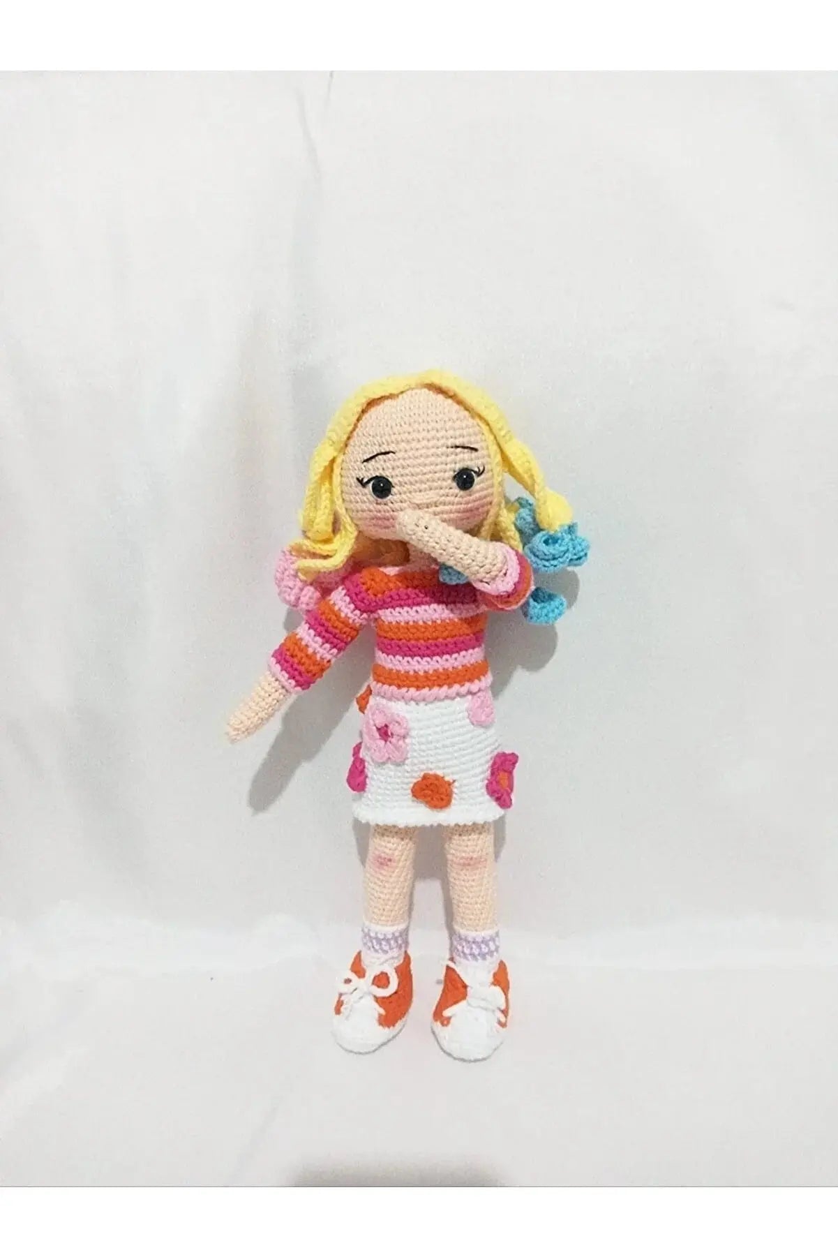 a crocheted doll is holding a toy