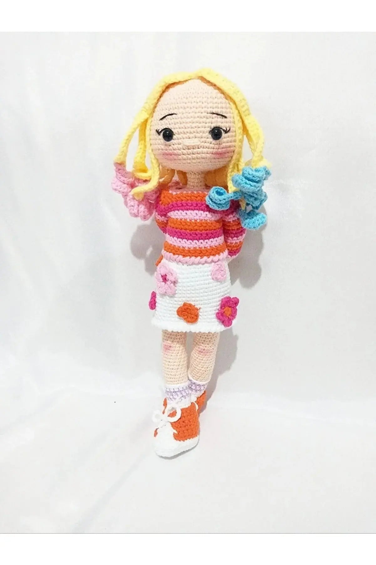 a crocheted doll with a flower in her hand