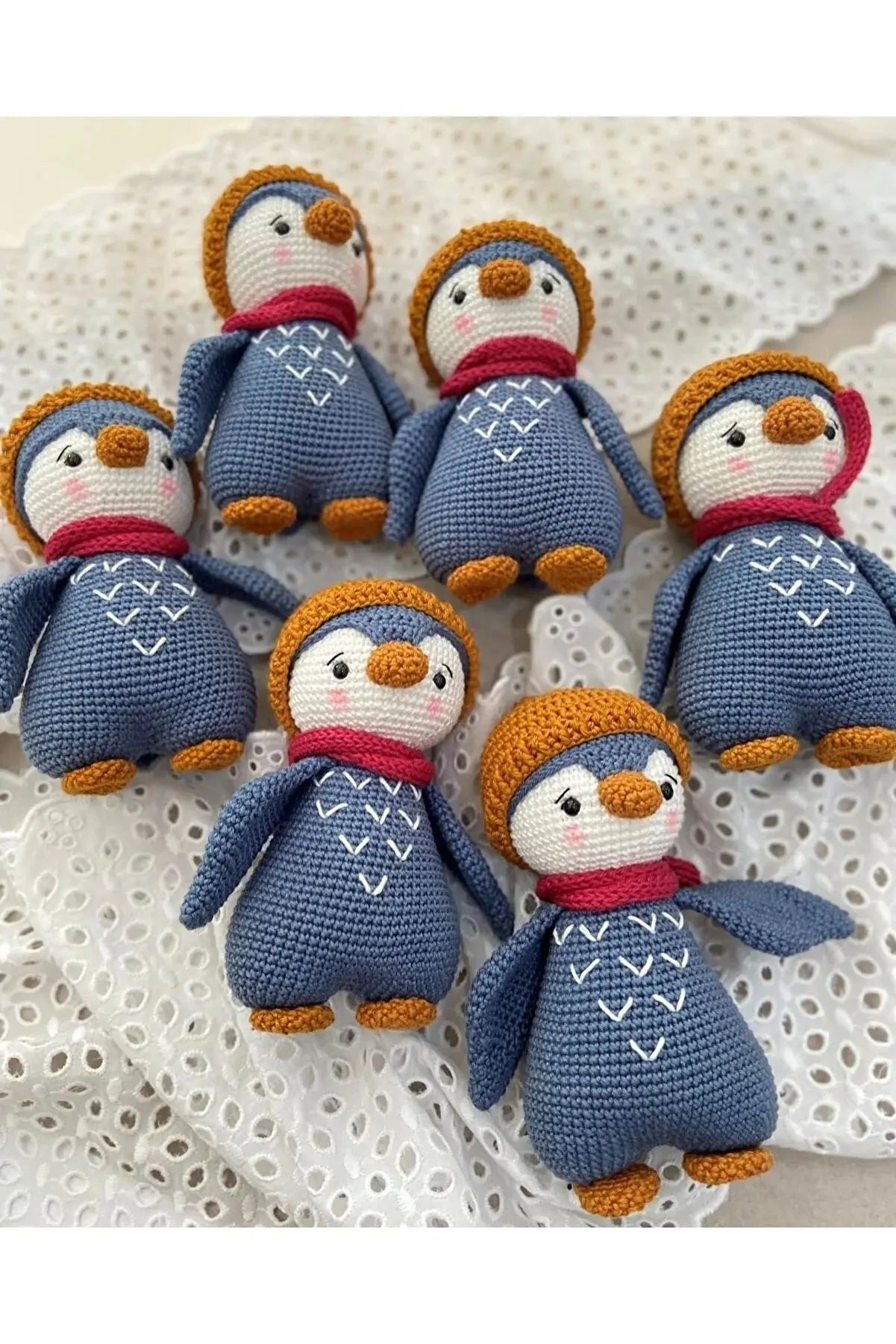 a group of knitted penguins sitting on top of a white doily