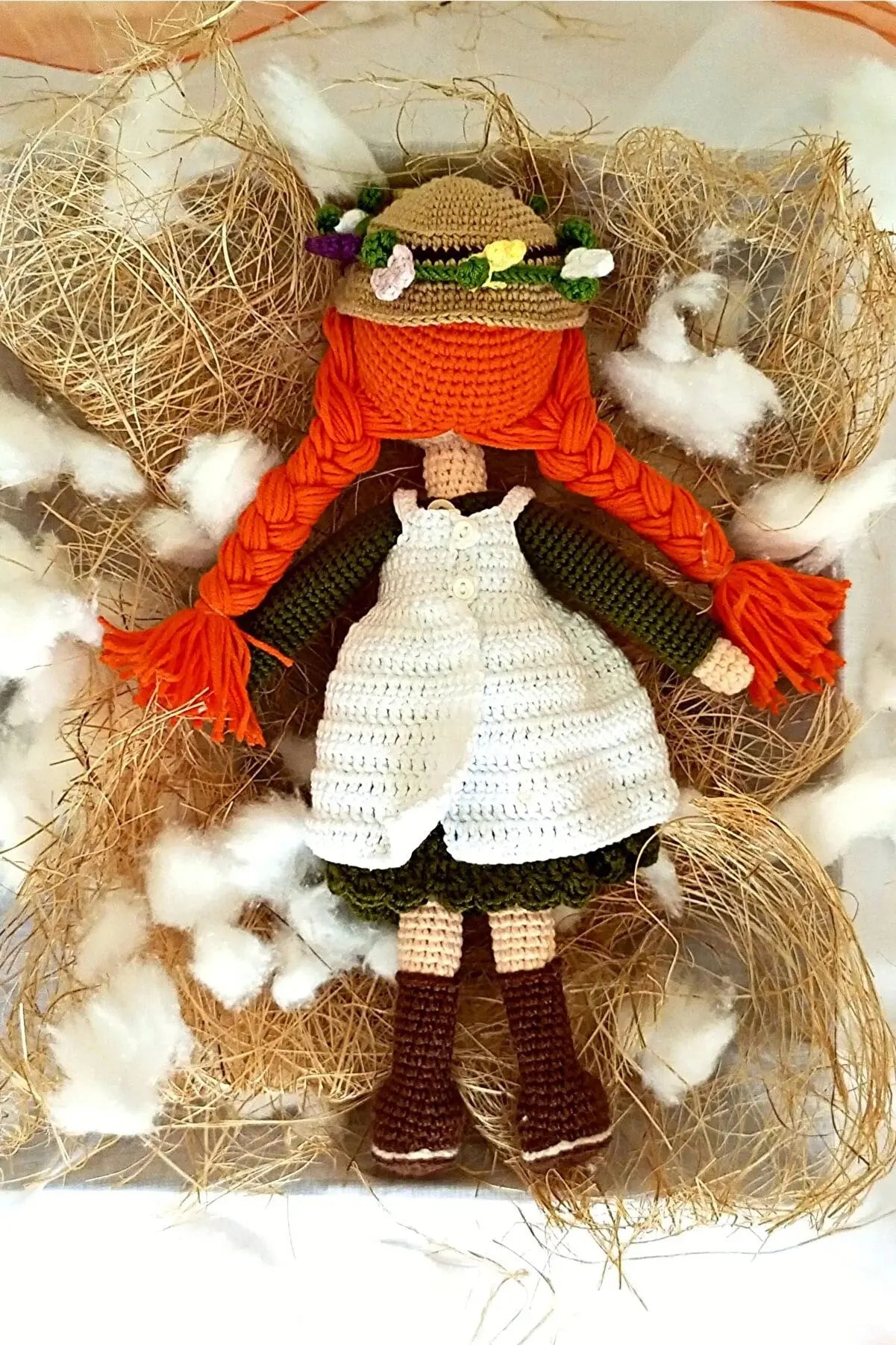 a crocheted doll is sitting in hay