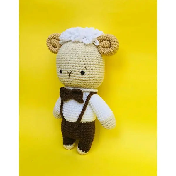 a crocheted teddy bear wearing a brown bow tie