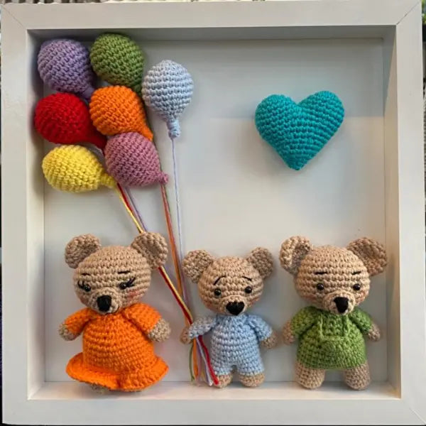 three crocheted teddy bears in a shadow box